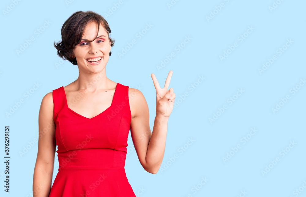 Fototapeta premium Beautiful young woman with short hair wearing casual style with sleeveless shirt smiling looking to the camera showing fingers doing victory sign. number two.