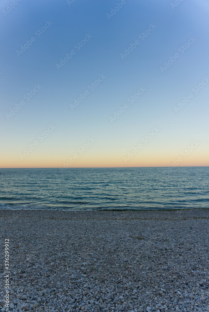 Fototapeta premium Orizzonte con tramonto e spiaggia piena di sassi