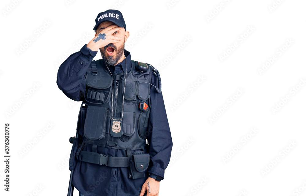 Young handsome man wearing police uniform peeking in shock covering face and eyes with hand, looking through fingers with embarrassed expression. Young handsome man wearing police uniform peeking in shock covering face and eyes with hand, looking through fingers with embarrassed expression.
