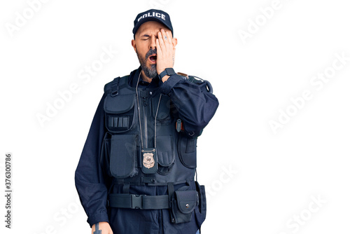 Young handsome man wearing police uniform yawning tired covering half face, eye and mouth with hand. face hurts in pain.