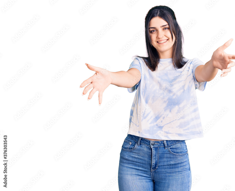 Young beautiful girl wearing casual t shirt looking at the camera smiling with open arms for hug. cheerful expression embracing happiness. Young beautiful girl wearing casual t shirt looking at the camera smiling with open arms for hug. cheerful expression embracing happiness.