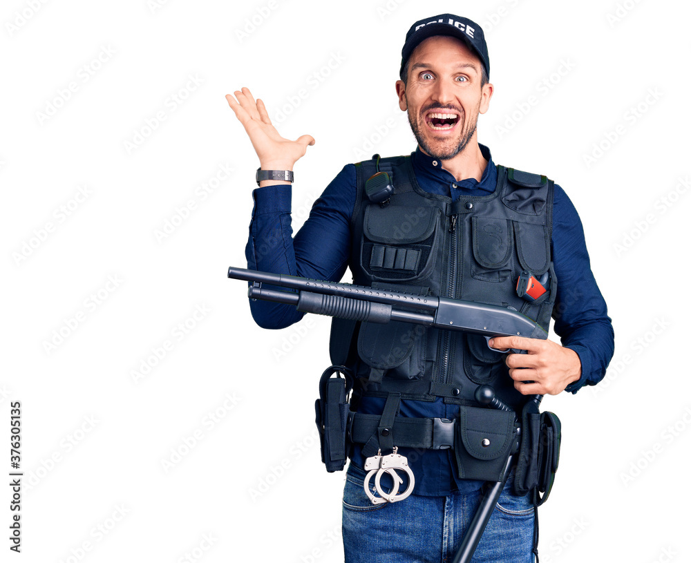 Young handsome man wearing police uniform holding shotgun celebrating victory with happy smile and winner expression with raised hands Young handsome man wearing police uniform holding shotgun celebrating victory with happy smile and winner expression with raised hands