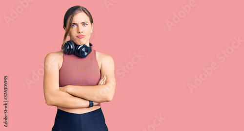 Beautiful caucasian young woman wearing gym clothes and using headphones skeptic and nervous, disapproving expression on face with crossed arms. negative person. © Krakenimages.com