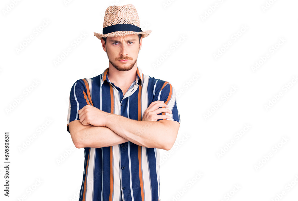 Young handsome caucasian man wearing summer hat skeptic and nervous, disapproving expression on face with crossed arms. negative person. Young handsome caucasian man wearing summer hat skeptic and nervous, disapproving expression on face with crossed arms. negative person.
