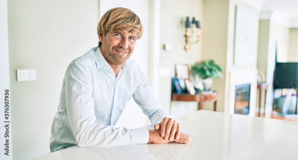 Young irish man smiling happy sitting on the table at home. Young irish man smiling happy sitting on the table at home.