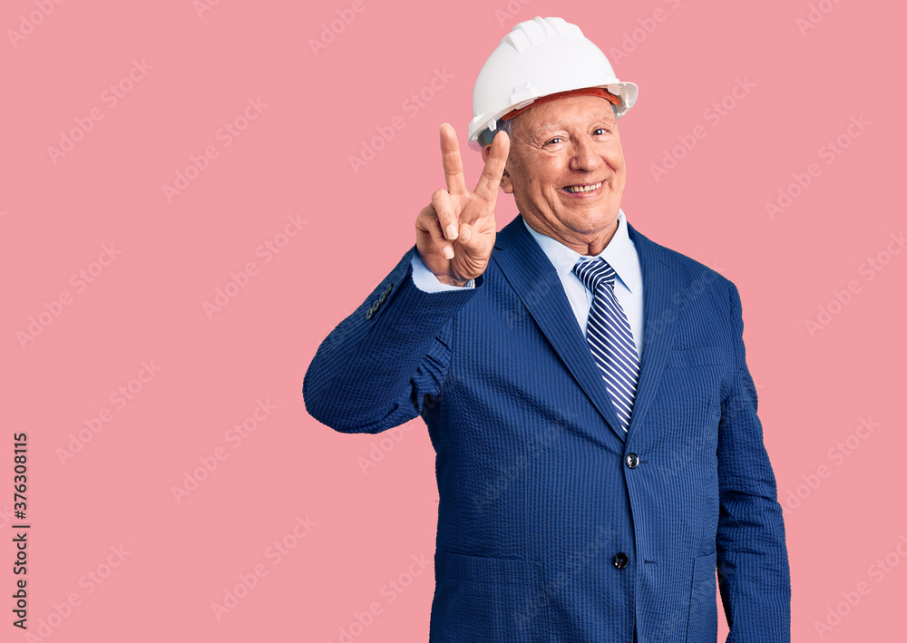 Senior handsome grey-haired man wearing suit and architect hardhat showing and pointing up with fingers number two while smiling confident and happy. Senior handsome grey-haired man wearing suit and architect hardhat showing and pointing up with fingers number two while smiling confident and happy.