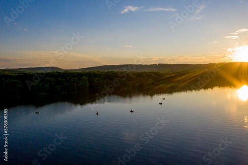 aerial view of fisherman at the boat on golden sunset river. silhouette of fishermen with his boat  Fisherman life style