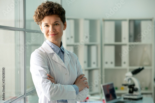 Happy young successful researcher in whitecoat standing in front of camera photo