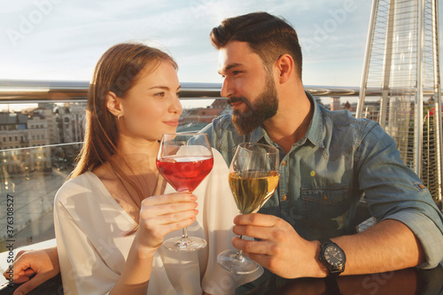 Charming young couple celebrating anniversary, drinking wine on sunset outdoors