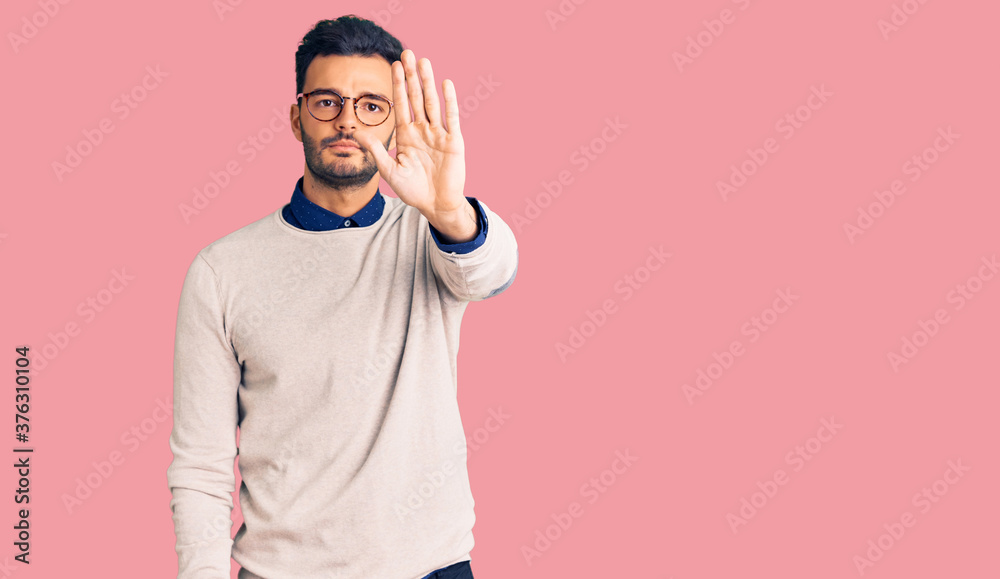 Young handsome hispanic man wearing elegant clothes and glasses doing stop sing with palm of the hand. warning expression with negative and serious gesture on the face. Young handsome hispanic man wearing elegant clothes and glasses doing stop sing with palm of the hand. warning expression with negative and serious gesture on the face.