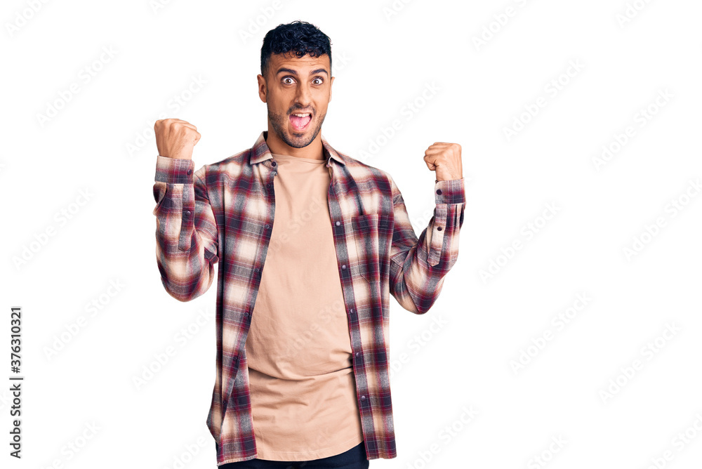 Fototapeta premium Young hispanic man wearing casual clothes screaming proud, celebrating victory and success very excited with raised arms