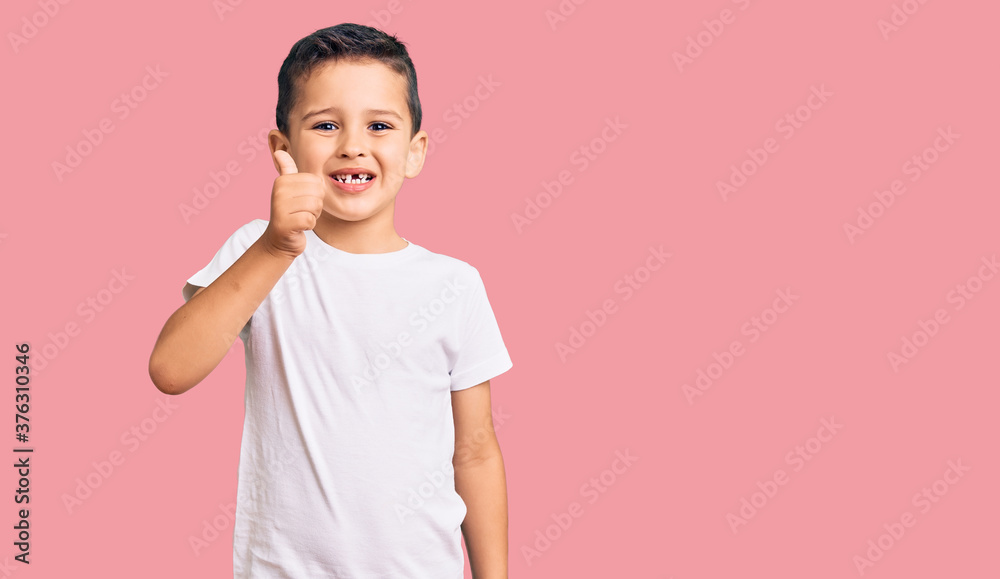 Little cute boy kid wearing casual white tshirt smiling happy and positive, thumb up doing excellent and approval sign Little cute boy kid wearing casual white tshirt smiling happy and positive, thumb up doing excellent and approval sign