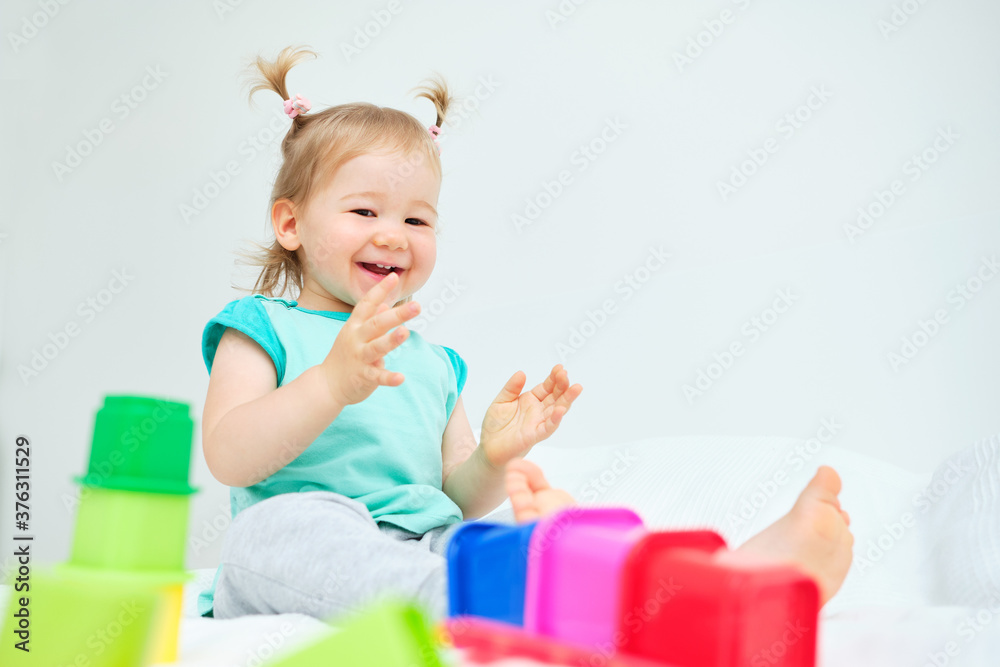 Caucasian kid smiling and clapping hands playing in colorful toys Caucasian kid smiling and clapping hands playing in colorful toys
