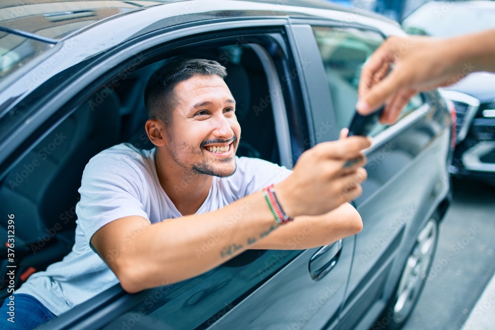 Young hispanic man smiling happy holding key of new car