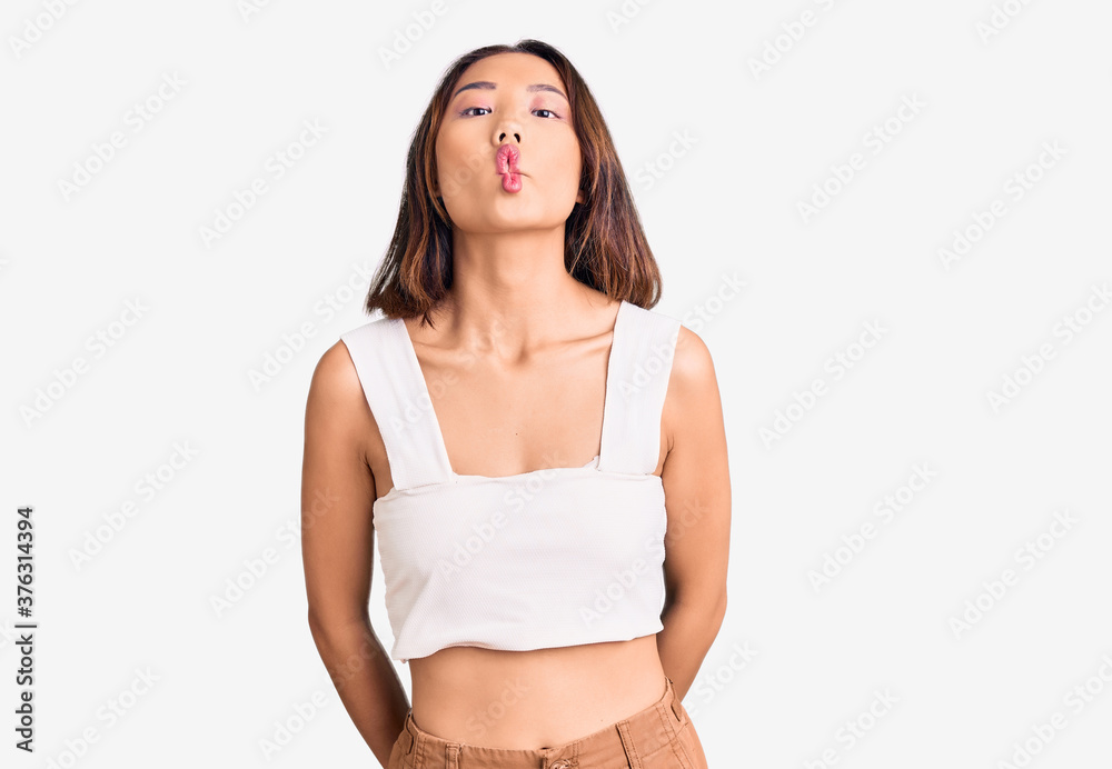 Young beautiful chinese girl wearing casual clothes making fish face with lips, crazy and comical gesture. funny expression. Young beautiful chinese girl wearing casual clothes making fish face with lips, crazy and comical gesture. funny expression.