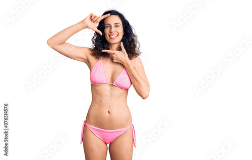 Young beautiful hispanic woman wearing bikini smiling making frame with hands and fingers with happy face. creativity and photography concept.