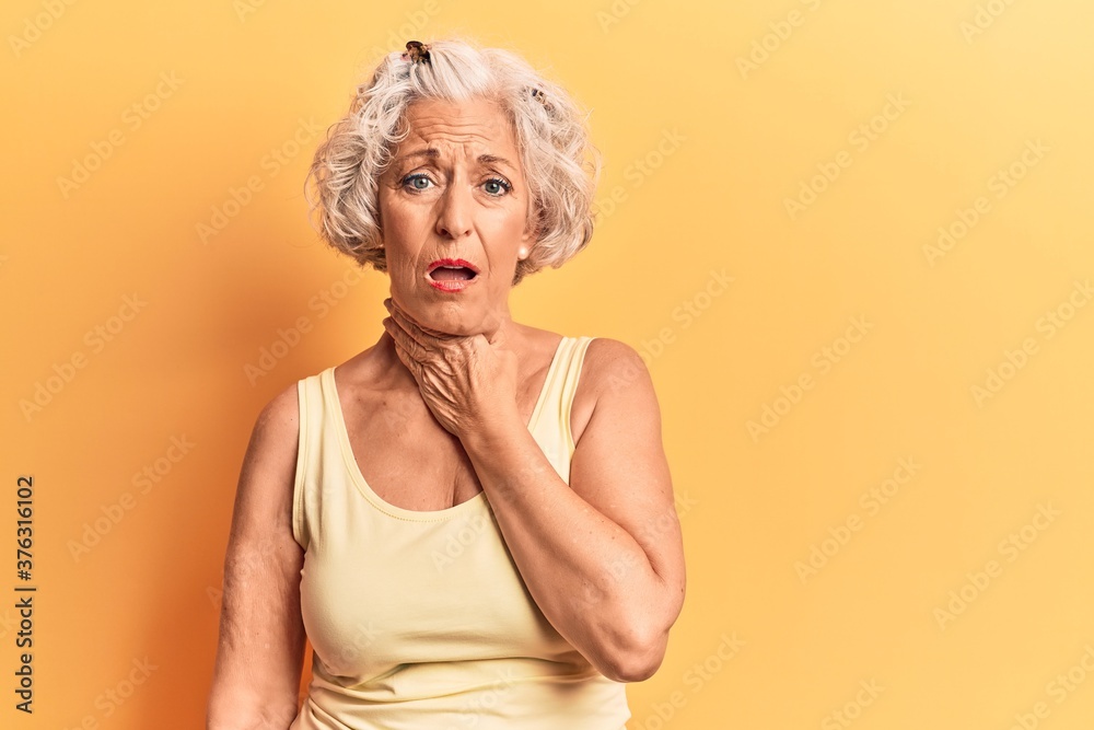 Senior grey-haired woman wearing casual clothes touching painful neck, sore throat for flu, clod and infection Senior grey-haired woman wearing casual clothes touching painful neck, sore throat for flu, clod and infection