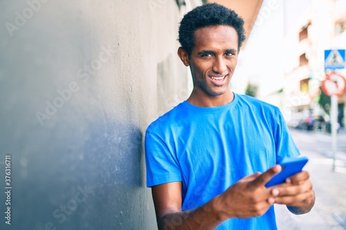 Handsome black african man smiling happy outdoors using smartphone