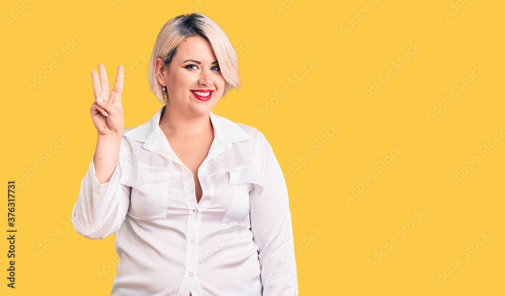 Young blonde plus size woman wearing casual shirt showing and pointing up with fingers number three while smiling confident and happy. Young blonde plus size woman wearing casual shirt showing and pointing up with fingers number three while smiling confident and happy.