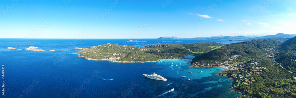 View from above, stunning panoramic view of the Grande Pevero beach with boats and luxury yachts sailing on a turquoise, clear water. Sardinia, Italy.