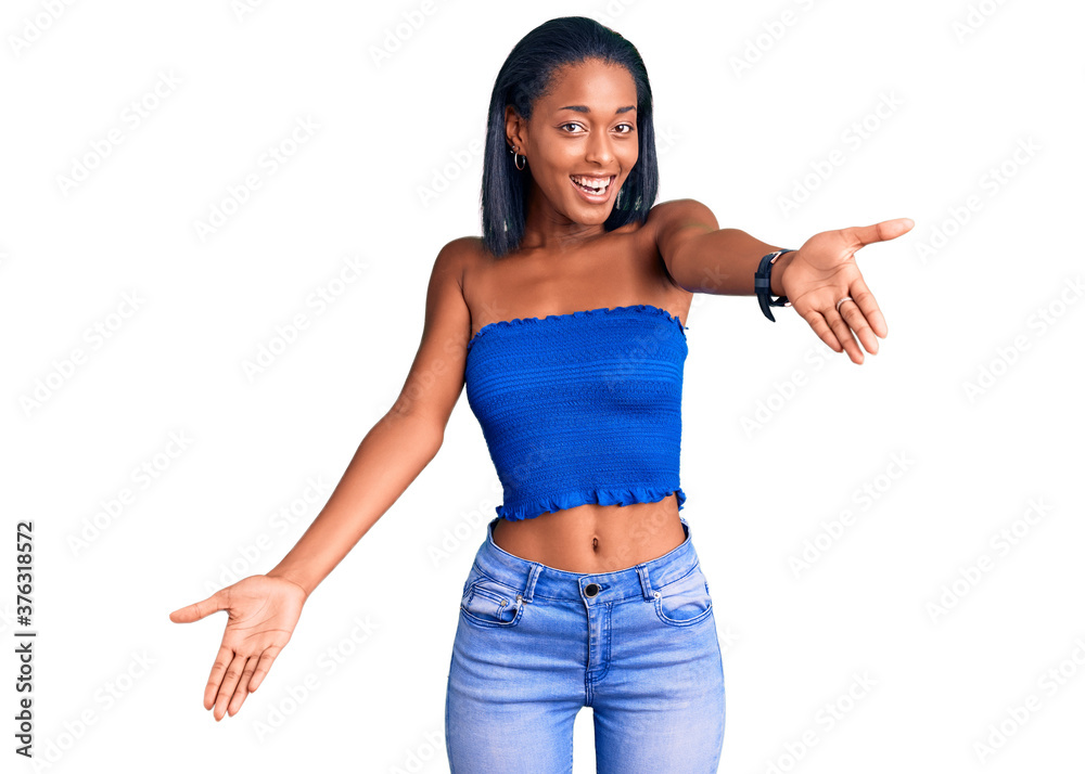 Young african american woman wearing casual summer clothes looking at the camera smiling with open arms for hug. cheerful expression embracing happiness. Young african american woman wearing casual summer clothes looking at the camera smiling with open arms for hug. cheerful expression embracing happiness.