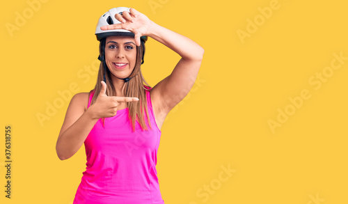 Young beautiful woman wearing bike helmet smiling making frame with hands and fingers with happy face. creativity and photography concept.