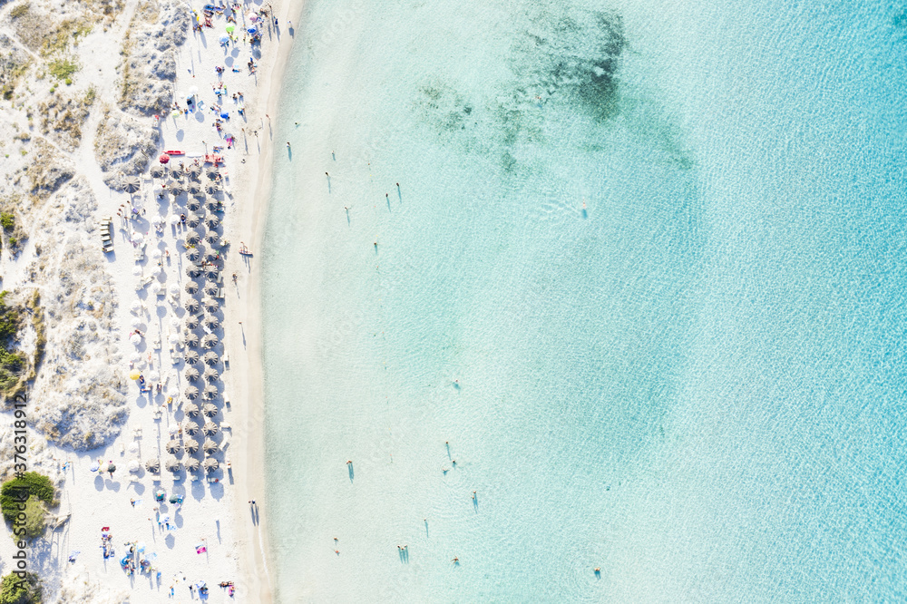 View from above, stunning aerial view of the Grande Pevero beach with beach umbrellas and people swimming in a turquoise, clear water. Sardinia, Italy.