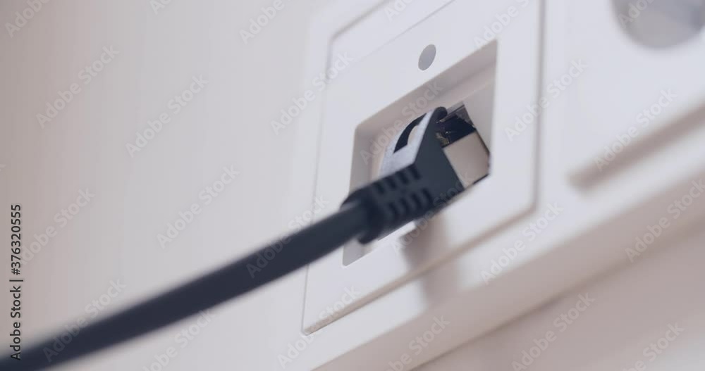 Hand plugging a computer network cable into a wall socket. Closeup shot. Hand plugging a computer network cable into a wall socket. Closeup shot.