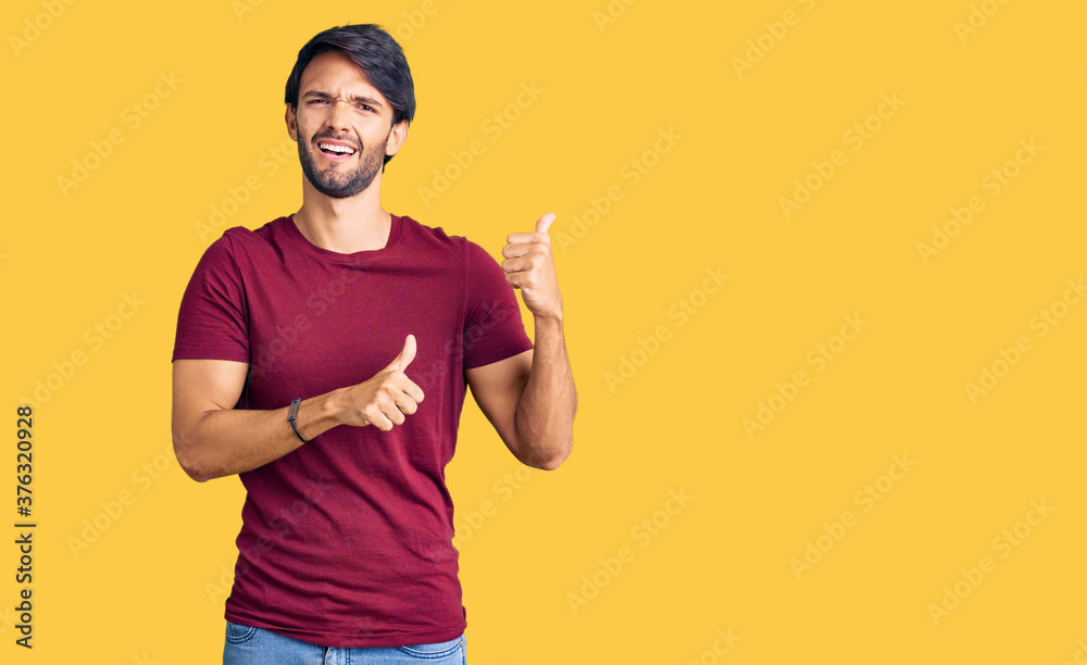 Handsome hispanic man wearing casual clothes pointing to the back behind with hand and thumbs up, smiling confident Handsome hispanic man wearing casual clothes pointing to the back behind with hand and thumbs up, smiling confident