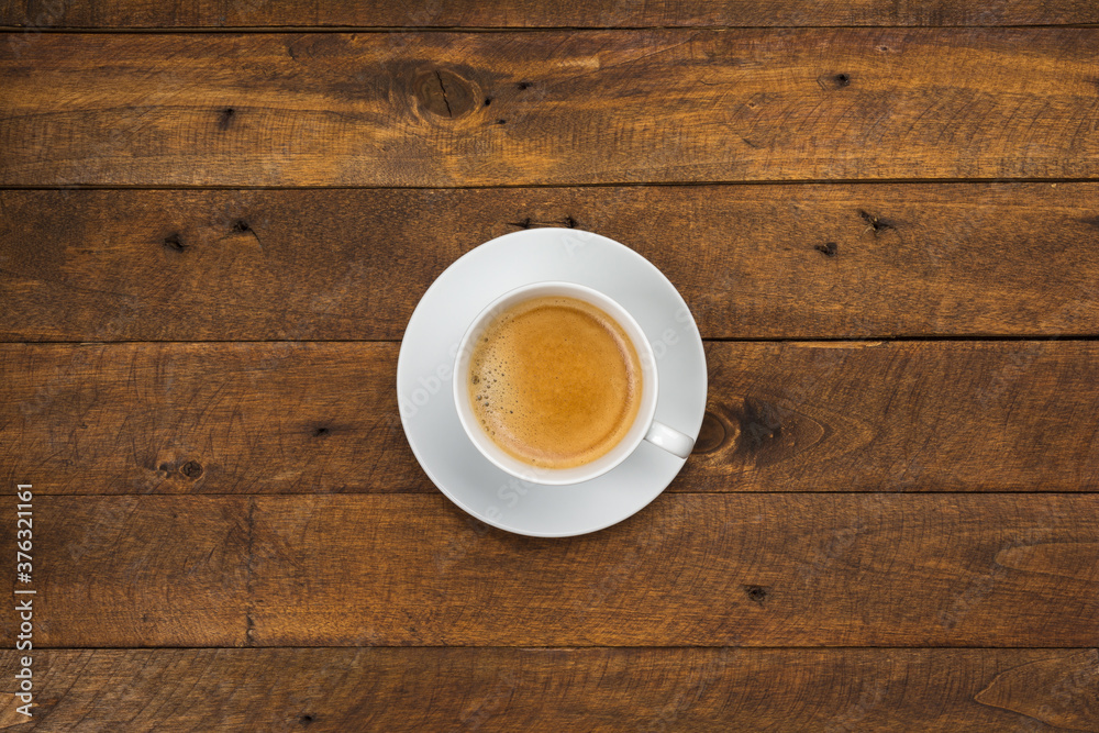 High angle view of coffee in white cup with saucer on old wooden background, close up High angle view of coffee in white cup with saucer on old wooden background, close up