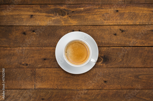 High angle view of coffee in white cup with saucer on old wooden background, close up