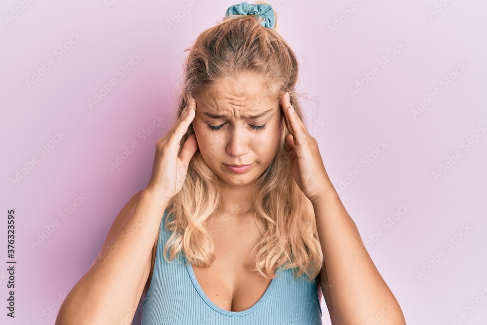 Young blonde girl wearing casual clothes with hand on head for pain in head because stress. suffering migraine. Young blonde girl wearing casual clothes with hand on head for pain in head because stress. suffering migraine.