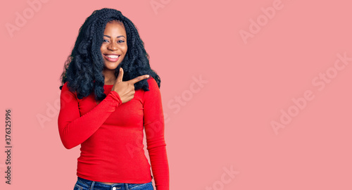 Beautiful african american woman wearing casual clothes cheerful with a smile of face pointing with hand and finger up to the side with happy and natural expression on face