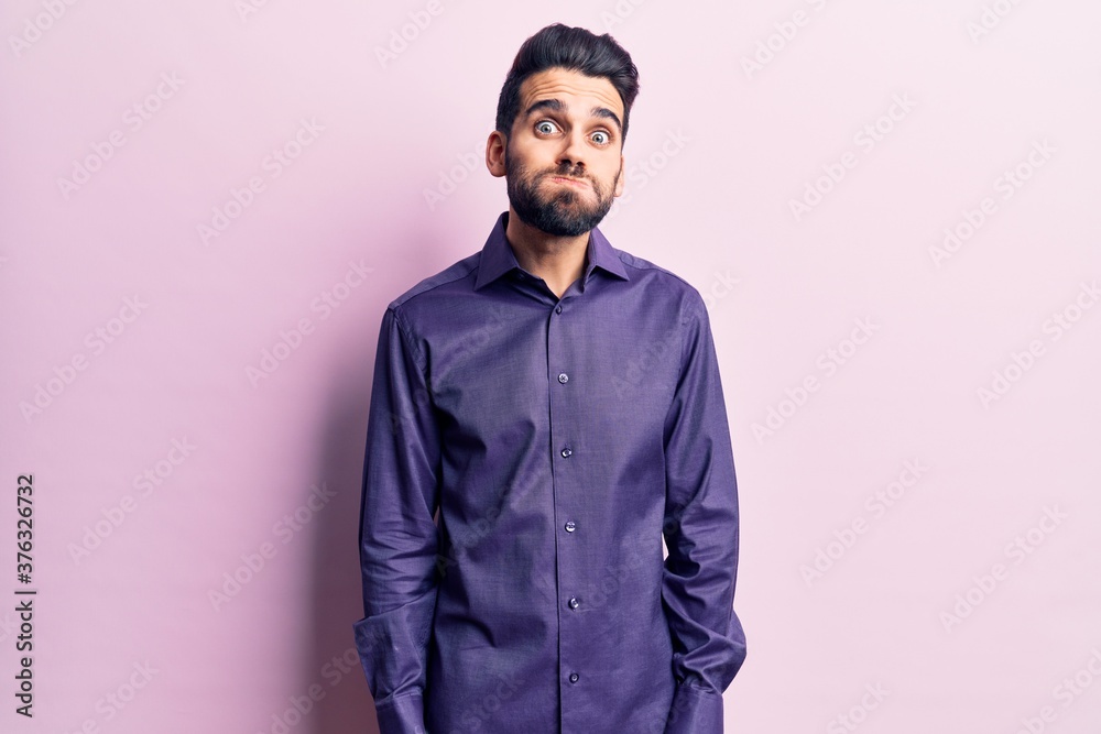Young handsome man with beard wearing casual shirt puffing cheeks with funny face. mouth inflated with air, crazy expression. Young handsome man with beard wearing casual shirt puffing cheeks with funny face. mouth inflated with air, crazy expression.