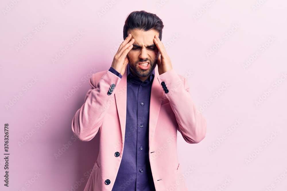 Young handsome man with beard wearing elegant jacket with hand on head for pain in head because stress. suffering migraine. Young handsome man with beard wearing elegant jacket with hand on head for pain in head because stress. suffering migraine.