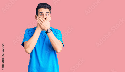 Young handsome man with beard wearing casual t-shirt shocked covering mouth with hands for mistake. secret concept.