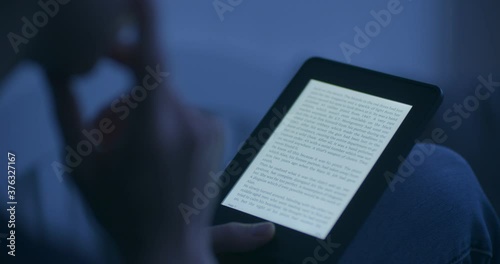 A woman reading an e-book in the evening or by night. photo