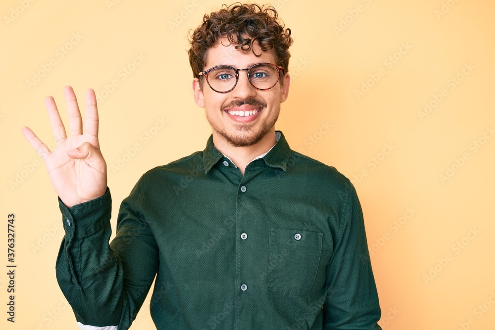 Young caucasian man with curly hair wearing casual clothes and glasses showing and pointing up with fingers number four while smiling confident and happy. Young caucasian man with curly hair wearing casual clothes and glasses showing and pointing up with fingers number four while smiling confident and happy.