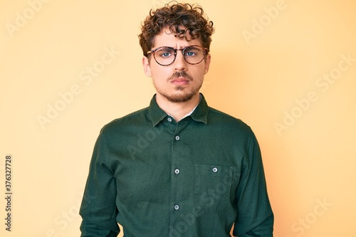 Young caucasian man with curly hair wearing casual clothes and glasses depressed and worry for distress, crying angry and afraid. sad expression.
