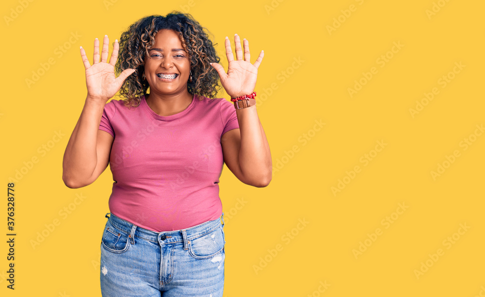 Young african american plus size woman wearing casual clothes showing and pointing up with fingers number ten while smiling confident and happy. Young african american plus size woman wearing casual clothes showing and pointing up with fingers number ten while smiling confident and happy.