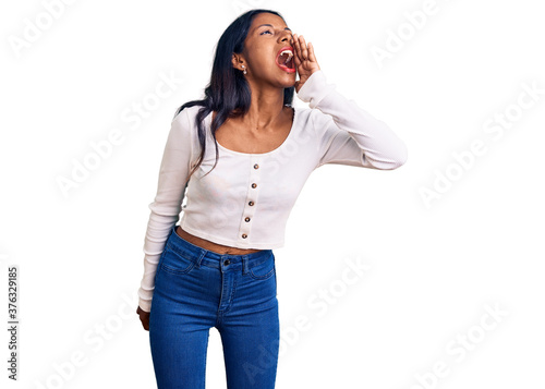 Young indian girl wearing casual clothes shouting and screaming loud to side with hand on mouth. communication concept. © Krakenimages.com