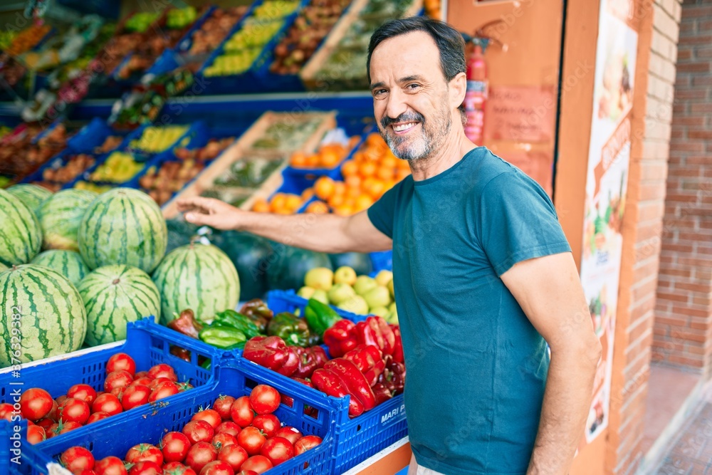 Middle age man with beard smiling happy shopping vegetables at the grocery supermarket