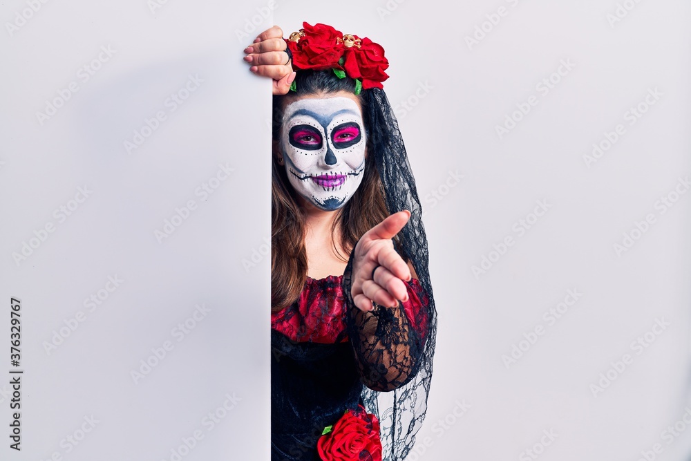 Young woman wearing day of the dead custome holding blank empty banner smiling friendly offering handshake as greeting and welcoming. successful business.
