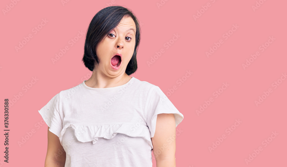 Brunette woman with down syndrome wearing casual white tshirt afraid and shocked with surprise and amazed expression, fear and excited face. Brunette woman with down syndrome wearing casual white tshirt afraid and shocked with surprise and amazed expression, fear and excited face.