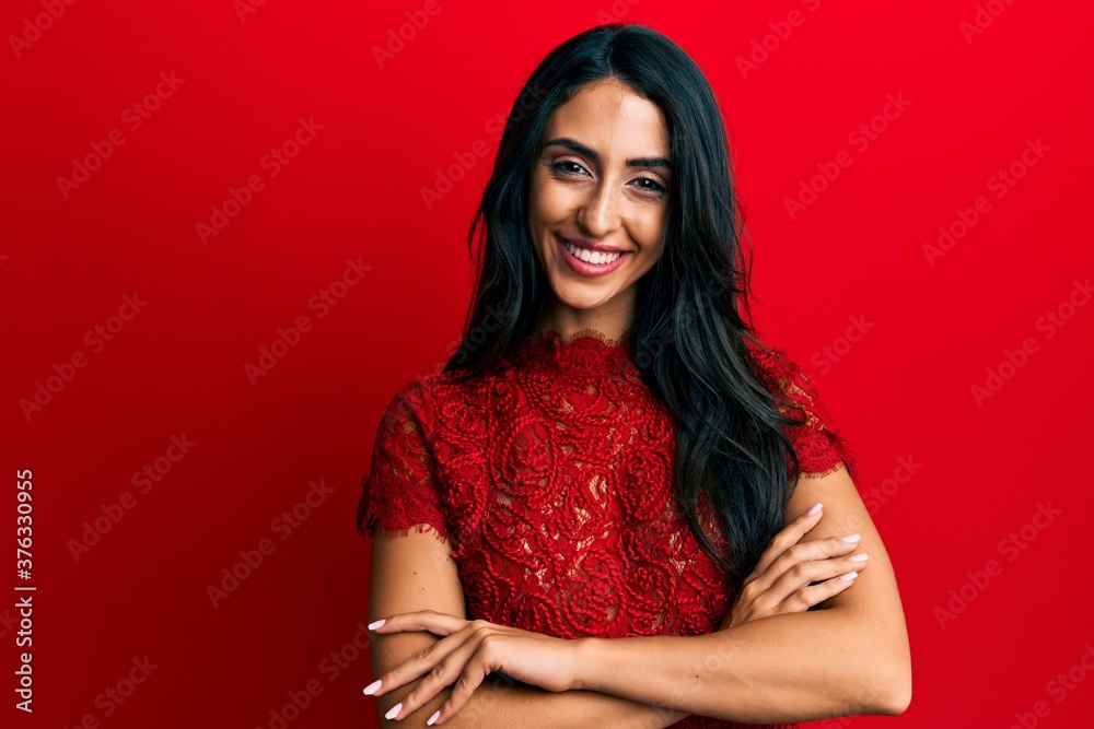Beautiful hispanic woman wearing elegant clothes over red background happy face smiling with crossed arms looking at the camera. positive person. Beautiful hispanic woman wearing elegant clothes over red background happy face smiling with crossed arms looking at the camera. positive person.
