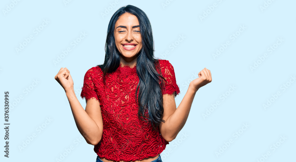 Beautiful hispanic woman wearing elegant shirt very happy and excited doing winner gesture with arms raised, smiling and screaming for success. celebration concept. Beautiful hispanic woman wearing elegant shirt very happy and excited doing winner gesture with arms raised, smiling and screaming for success. celebration concept.