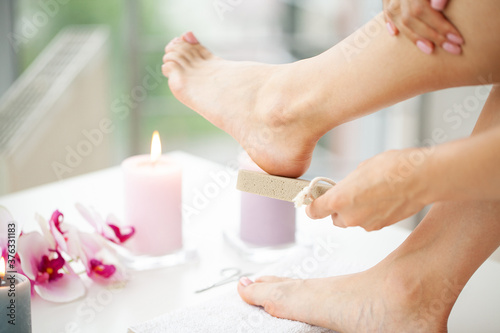 Woman cleans the heel of the foot with pumice photo