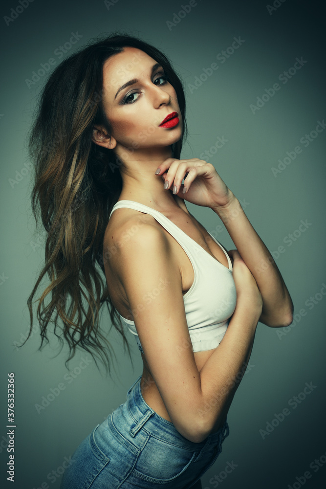 Naklejka premium fashion and people concept: woman wearing jeans posing over grey background