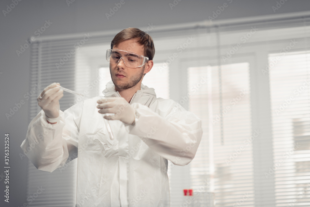 A concentrated young scientist working attentively with a pipette in laboratory, close up shot. A concentrated young scientist working attentively with a pipette in laboratory, close up shot.