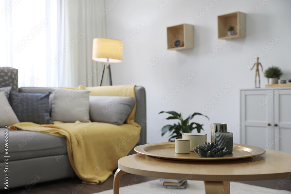 Wooden table with candles and tray near sofa in living room. Interior design Wooden table with candles and tray near sofa in living room. Interior design